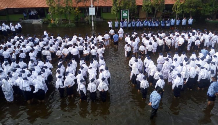 Meski halaman sekolahnya tergenang banjir, pelajar dan guru di SMPN 2 Tanggulangin tetap antusias mengikuti upacara bendera, Senin (17/2)/Foto: Satria/Sidoarjonews.id