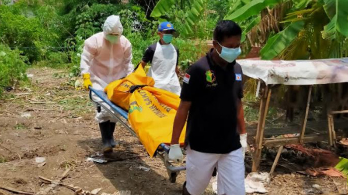 Petugas mengevakuasi mayat pria yang ditemukan sudah membusuk di kebun Singkong di belakang makam desa Pamotan, Kecamatan Porong, Sidoarjo.