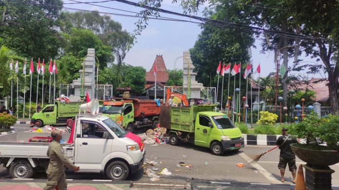 Petugas kebersihan saat membersihkan tumpukan sampah yang dibuang massa aksi di depan pintu gerbang Pendopo Delta Wibawa/Foto : Istimewa