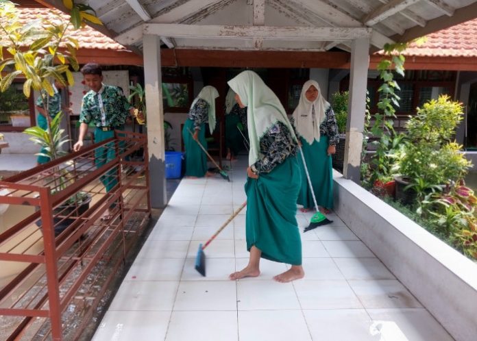 FOTO: Sebagian siswa SMPN 2 Tanggulangin saat membersihkan lantai di depan ruang kelas yang sempat terendam banjir/Foto: Ipung Syaiful