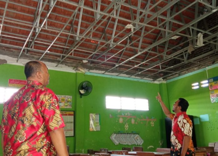 Salah seorang guru SDN Wangkal menunjukkan kondisi plafon di ruang kelas yang ambrol/Foto: Ipung Syaiful