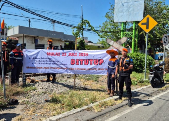 Petugas KAI saat membentang spanduk pemberitahuan penutupan dua perlintasan kereta api sebidang di Flyover Juanda/Foto: Istimewa