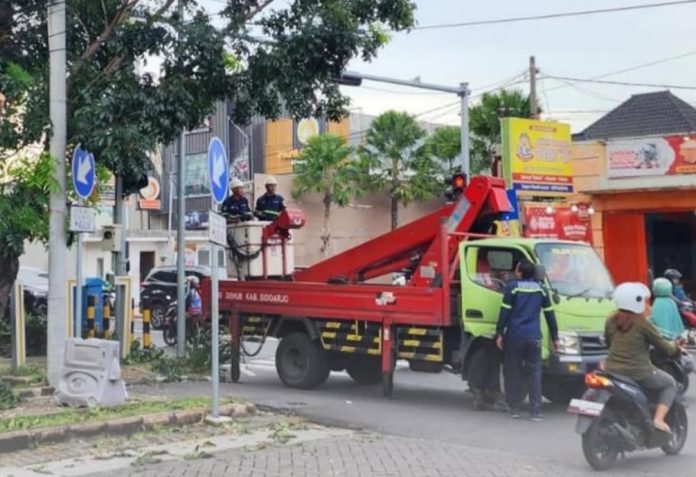 Petugas Dishub Sidoarjo saat membenahi PJU yang bermasalah/Foto: Istimewa