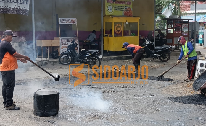 Sejumlah pekerja sedang memperbaiki jalan rusak di Desa Sepande Kecamatan Candi, Sidoarjo/Foto: Ipung Syaiful